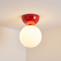 Close view of the red Vellona flush mount ceiling light against a plain white ceiling and cream wall