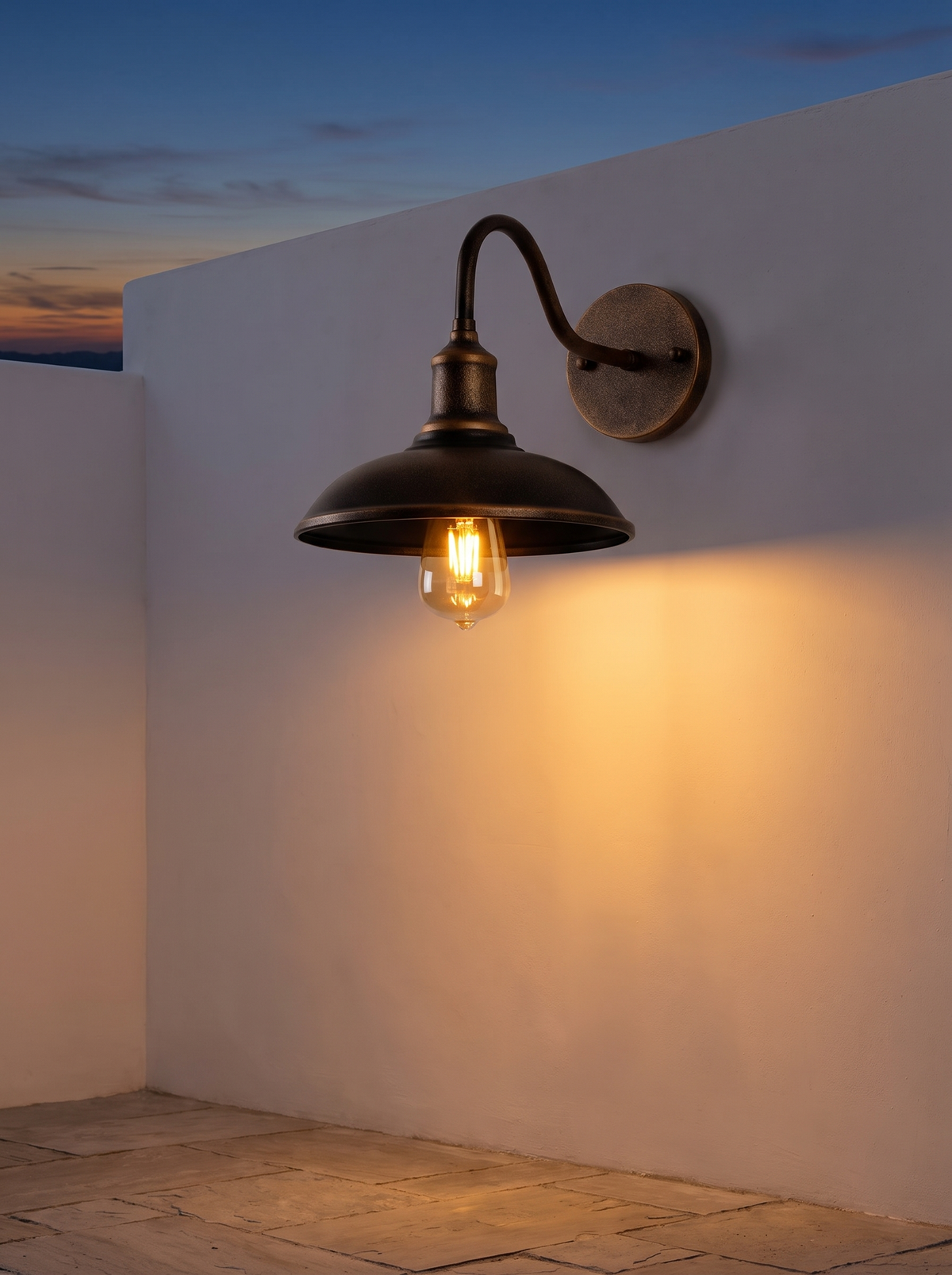 Bolva Bowl Outdoor Wall Light - antique brass bowl shade glowing warm at dusk on rendered courtyard wall