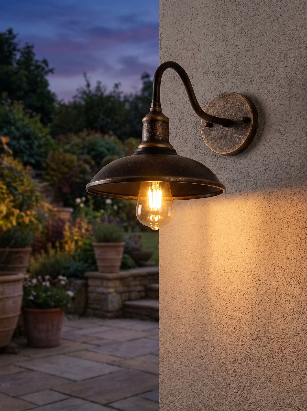 Bolva Bowl Outdoor Wall Light - antique brass gooseneck wall light glowing at dusk on garden patio with terracotta pots