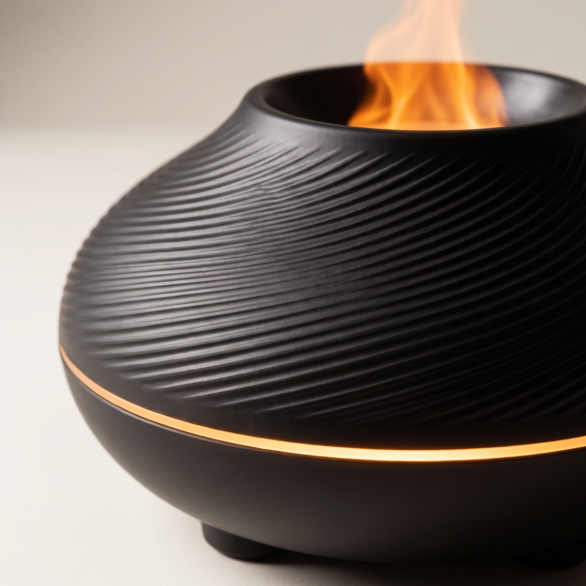 Volcano Flame Diffuser - macro detail of matte black swirl-ribbed texture and amber equatorial ring