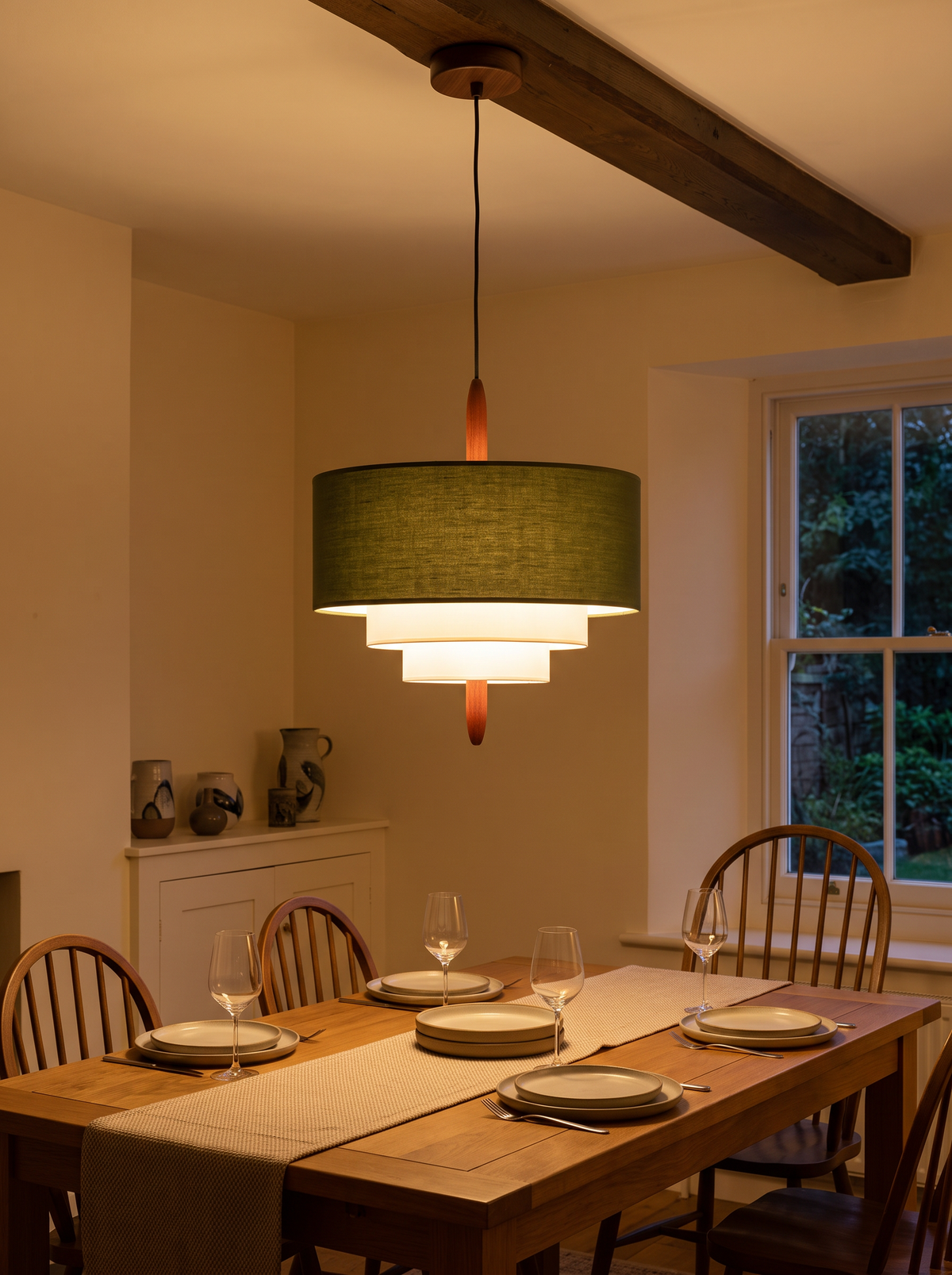 Verda Fabric Drum Pendant Light - green linen drum shade with tiered white diffusers glowing warm above oak dining table