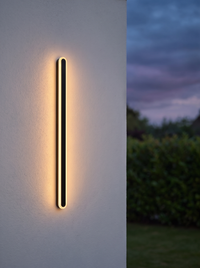 Orvo Linear Oval Outdoor Wall Light - single unit glowing warm amber at dusk on rendered exterior wall
