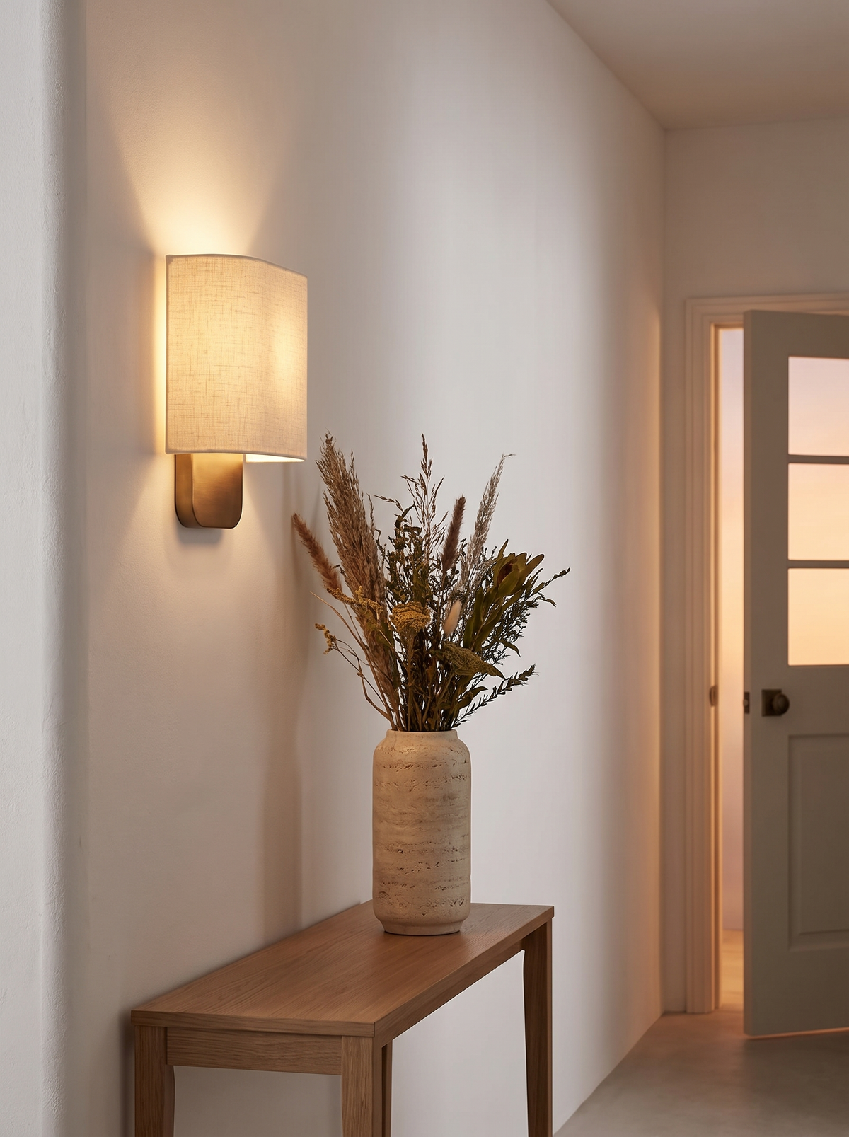 Lino Curved Linen Wall Light - hallway lifestyle with warm 2700K glow above oak console and dried grasses