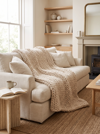Cloud Chunky Knit Throw - scale lifestyle shot draped over linen sofa in warm UK living room