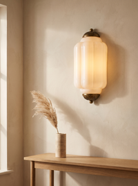 Faro Flush Milk Glass Wall Light - warm glowing lifestyle on cream limewashed wall above oak console with pampas in travertine vase