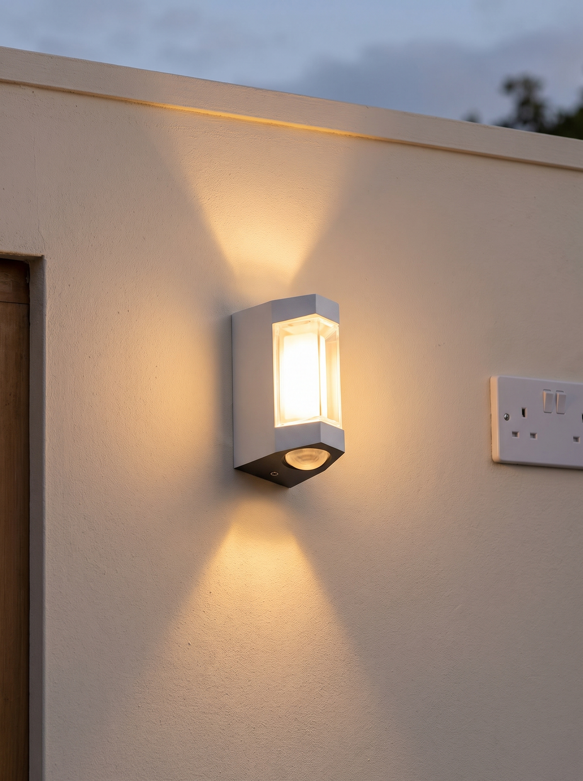 Marvo Up-Down Outdoor Wall Light - scale shot beside UK double socket on cream render wall, warm 2700K beams up and down