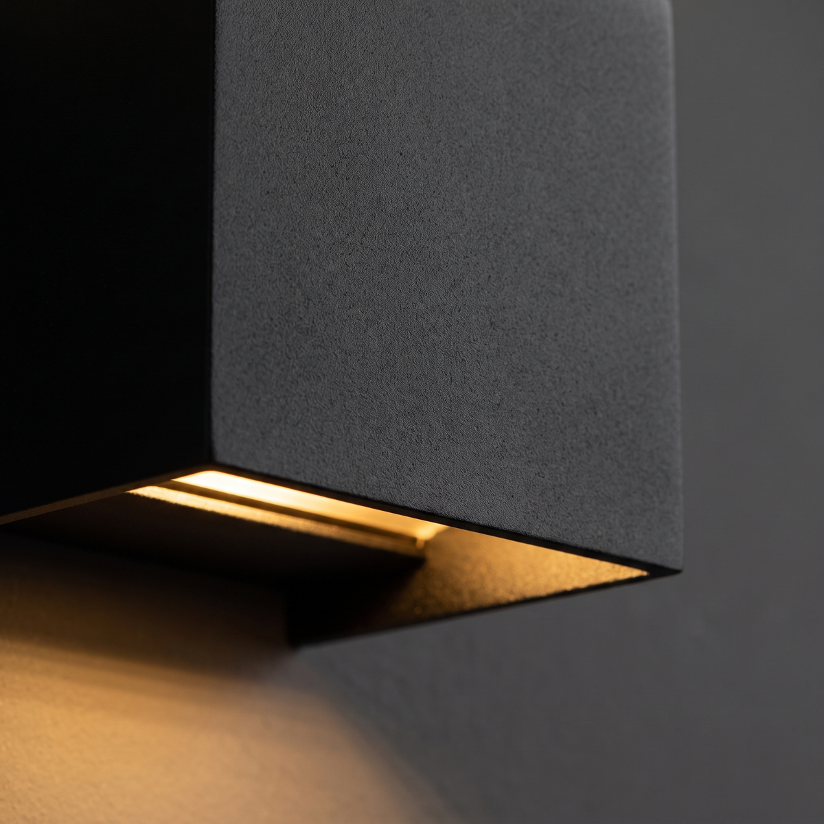 Nexo Adjustable Square Outdoor Wall Light - macro close-up of matte black cube face and warm amber LED light slot