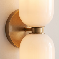 Solia Twin Glass Wall Sconce - macro close-up of opal glass shades and brushed brass disc junction showing warm translucent glow