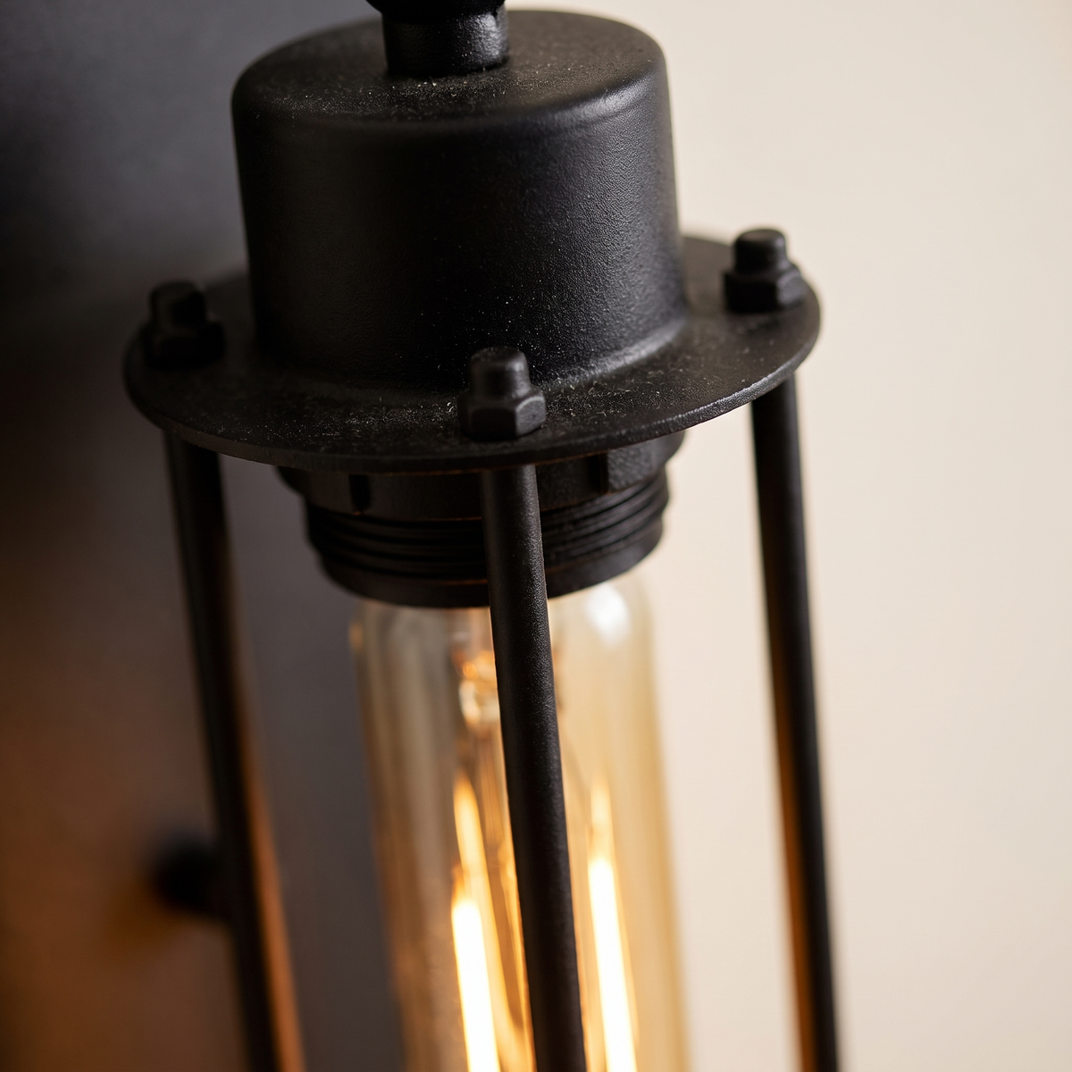 Trono Cylinder Wall Light - macro close-up of matte black steel cage rods, end cap detail and warm glowing tubular filament