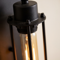Trono Cylinder Wall Light - macro close-up of matte black steel cage rods, end cap detail and warm glowing tubular filament