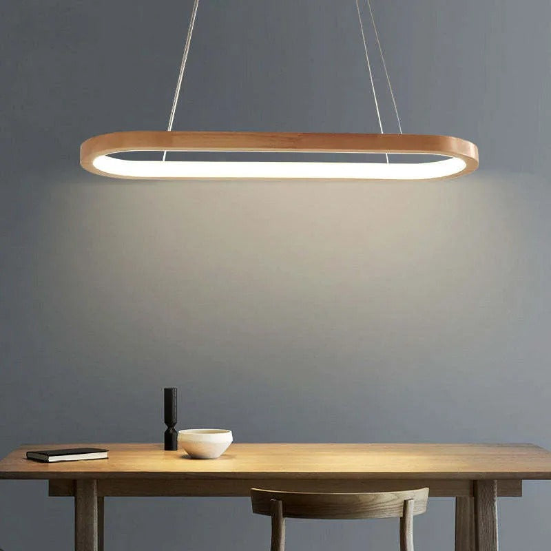 Veona oval wood pendant light casting a warm pool of light over a wooden dining table