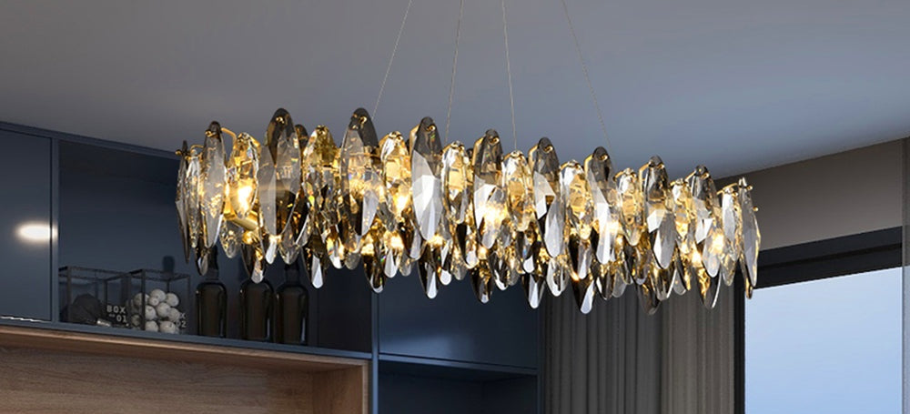 Ondra gold crystal chandelier lit in a navy blue dining room with wood cabinetry