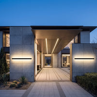 Sela linear wall light glowing on a house facade at dusk