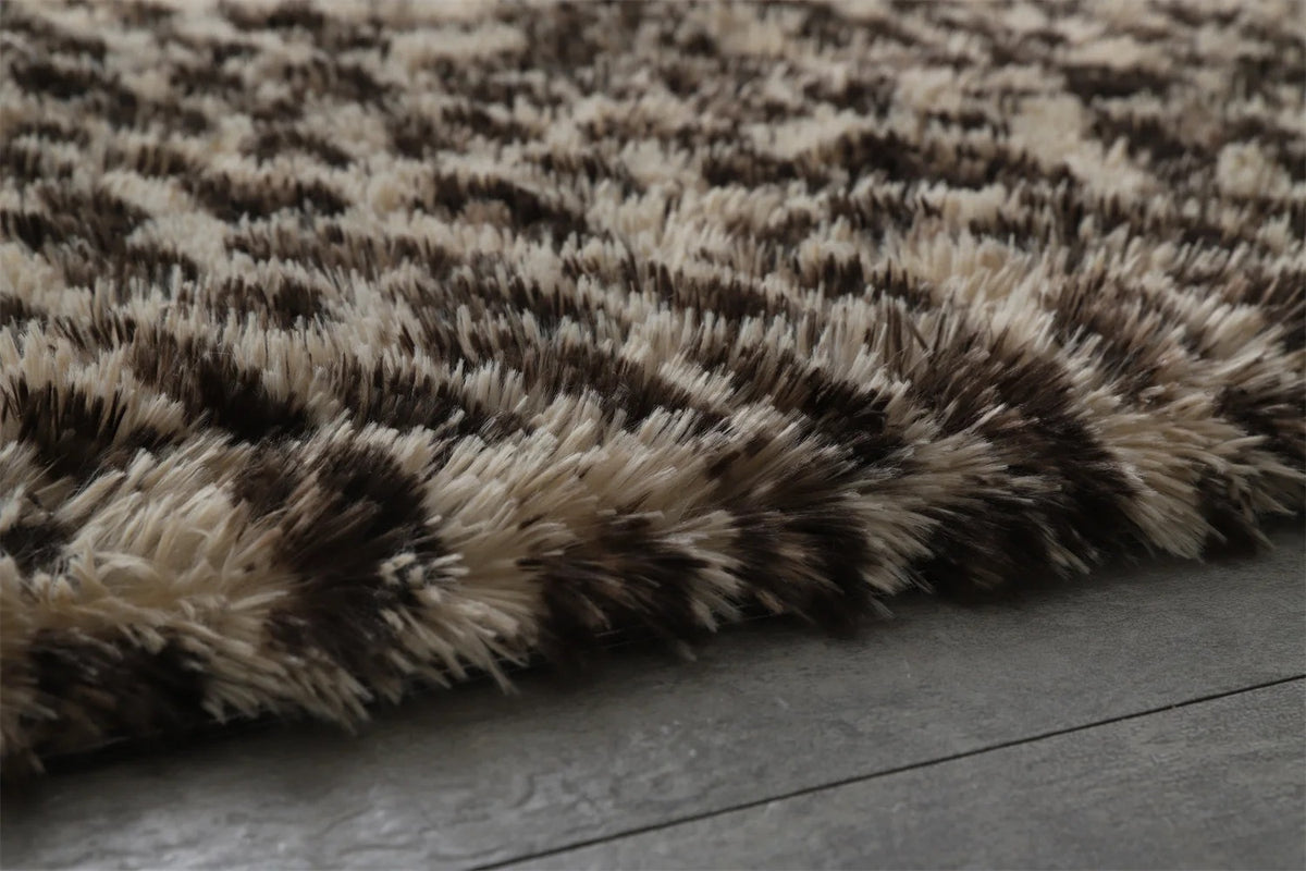 Close-up macro of the Fauna Shag Rug pile, showing the long flocked polyester fibres shading from cream to dark chocolate