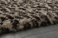 Close-up macro of the Fauna Shag Rug pile, showing the long flocked polyester fibres shading from cream to dark chocolate