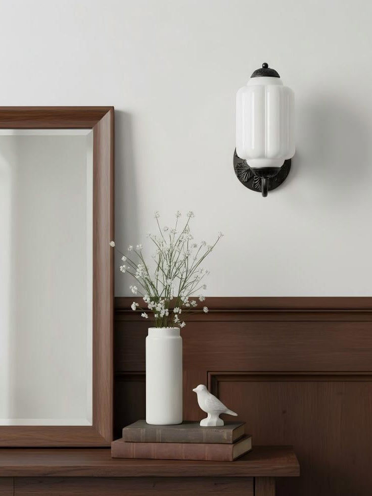 Elva milk glass wall sconce on a pale wall above a console and mirror